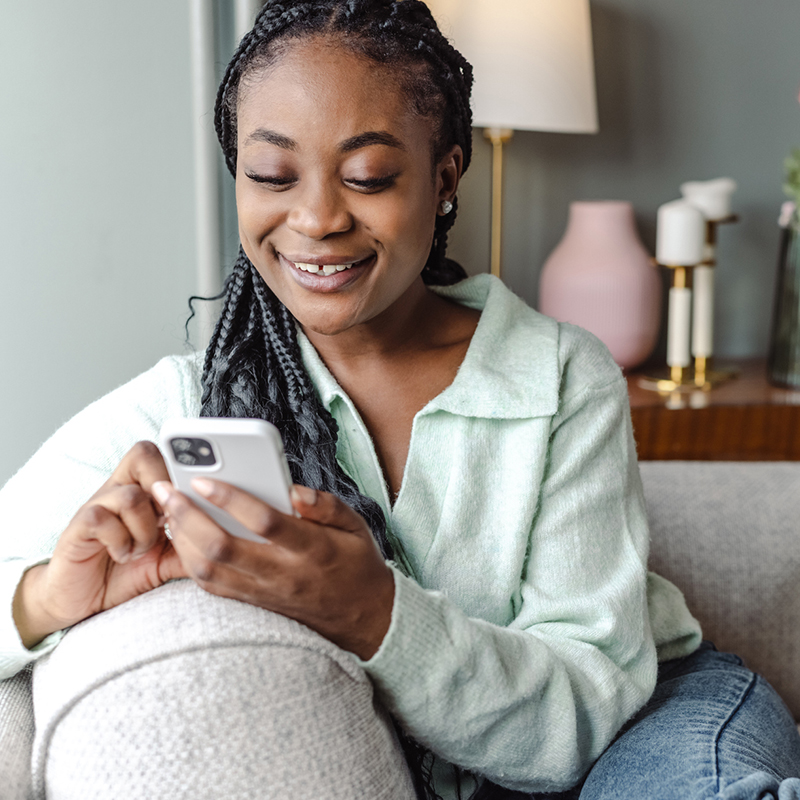 Woman sitting on couch with phone checking insurance coverage